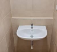 Waschbecken im Badezimmer eines Einzimmerapartments mit Fliesen in neutralen Tönen.