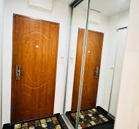 Flur in einer 3-Zimmer-Wohnung mit Türen, einem Spiegelschrank und einem bunten Teppich.