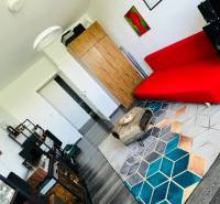 Wohnzimmer in einer 3-Zimmer-Wohnung mit einem roten Sofa und einem Boden in Holzoptik.