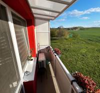 Der Balkon einer 3-Zimmer-Wohnung in Gbeľoch mit Blick auf grüne Wiesen und Blumen.