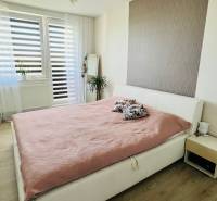 Helles Schlafzimmer mit großem Bett, Spiegel und Holzboden in einer 3-Zimmer-Wohnung.