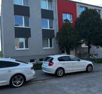 Ein Wohnhaus in Gbely mit moderner Fassade und geparkten Autos vor einer 3-Zimmer-Wohnung.