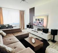 Wohnzimmer mit Ecksofa, TV-Schrank und Boden mit Holzdekor.