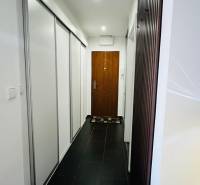 Ein schmaler Flur mit schwarzem Boden und weißen Einbauschränken in einer 3-Zimmer-Wohnung.