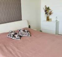 Schlafzimmer in einer 3-Zimmer-Wohnung mit Bett, dekorativen Kissen und ornamentaler Tapete.
