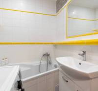 Badezimmer der Ferienwohnung mit Badewanne, Waschbecken, Waschmaschine und weißen Fliesen.