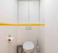 Badezimmer mit weißen Fliesen und gelben Details im Ferienapartment.
