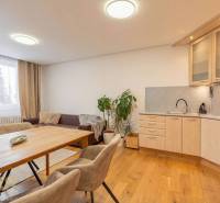 Innenraum einer Ferienwohnung mit Sofa, Küche und Holzboden.