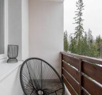 Balkon einer Ferienwohnung in Poprad mit einem schwarzen Sessel und Blick auf die Bäume.