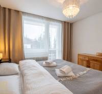Schlafzimmer in einer Ferienwohnung mit Doppelbett und Kommode, Fenster mit Aussicht.
