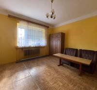 Žltá izba v rodinnom dome s dvomi kreslami a stolom, podlaha s dreveným dekorom.