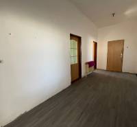 Interiér rodinného domu s podlahou s dreveným dekorom a bielymi stenami.