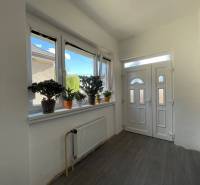 Vstupná hala v rodinnom dome s podlahou s dreveným dekorom a rastlinami na parapete.