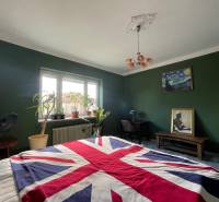 Spálňa v rodinnom dome s odvážnou dekoráciou v britskom štýle a zelené steny.