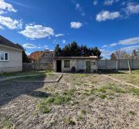 Záhrada pri rodinnom dome na ulici Heď v Čiernom Brode s nízkymi stavbami a plotom.