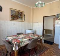 Kuchyňa v rodinnom dome s kvetinovým obrusom, stoličkami a podlahou s dreveným dekorom.