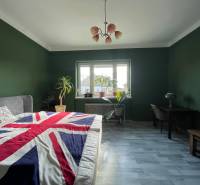 Spálňa v Rodinnom dome s tmavozelenými stenami a posteľou s britskou vlajkou.