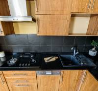 Küchenzeile in einer 2-Zimmer-Wohnung, mit Holzboden und dunklen Fliesen.