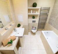 Badezimmer in einer 2-Zimmer-Wohnung mit Badewanne, Waschbecken, Spiegel und Handtuchhalter.