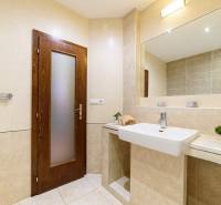 Badezimmer in einer Zweizimmerwohnung mit beigen Fliesen und einer Pflanze auf dem Regal.