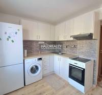 Küche in einer Einzimmerwohnung mit weißen Schränken und Holzboden.