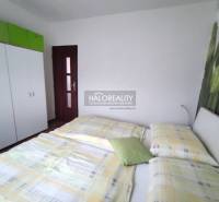 Schlafzimmer in einer 4-Zimmer-Wohnung mit Bett, Schrank und dekorativer Wand mit Blume.