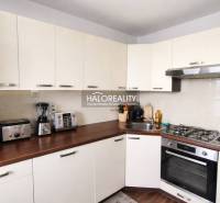 Küche in einer 4-Zimmer-Wohnung mit weißen Schränken und einem Boden in Holzoptik.