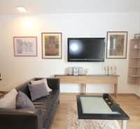 Wohnzimmer in einer Einzimmerwohnung mit schwarzem Sofa und Holzboden-Dekor.