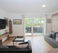 Wohnzimmer in einer Einzimmerwohnung mit Fernseher, Sofas und Holzboden.