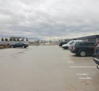 Parkplatz in der Broskyňová-Straße in der Stadt Rovinka mit Autos und Wohngebäuden im Hintergrund.