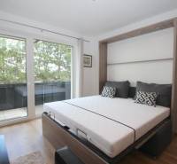 1-Zimmer-Wohnung mit Blick auf den Balkon und einem Bett in der intelligenten Wand.