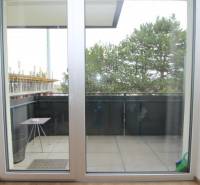 Balkon mit Schiebetüren und Blick auf Bäume in einer Einzimmerwohnung in der Broskyňová-Straße in Rovinka.