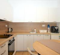 Weiße Küche mit Holzdekor in einer Einzimmerwohnung mit Geräten.
