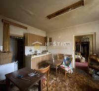 Küche in einem Einfamilienhaus mit Holzmöbeln, einem alten Fernseher, einem Esstisch und einem Kleiderschrank.