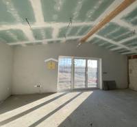 Unvollendetes Zimmer in einem Einfamilienhaus mit Fenstern und Blick auf den Garten.