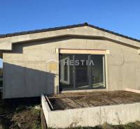 Ein Einfamilienhaus in der Stadt Sekule mit einer unvollendeten Terrasse und großen Glastüren.