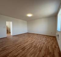 Ein Zimmer in einem Einfamilienhaus mit einem Boden in Holzoptik und weißen Wänden.