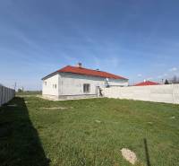 Ein Einfamilienhaus in Zemianska Olča mit weißer Fassade und rotem Dach auf einem grasbewachsenen Grundstück.