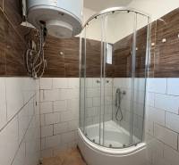 Badezimmer in einem Einfamilienhaus mit Eckdusche, elektrischem Boiler und braunen Fliesen.