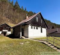 Eine Hütte in Moštenica, umgeben von Natur und Wald, mit klarem Himmel und einer grasbewachsenen Fläche.