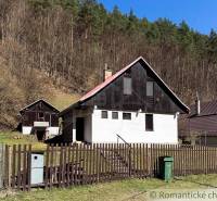 Eine Hütte in Moštenica, umgeben von Wäldern, mit einem Zaun und einem Mülleimer im Hof.