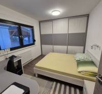 Schlafzimmer in einem Einfamilienhaus mit Bett, Schreibtisch und Schrank.