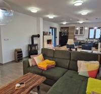 Wohnzimmer eines Einfamilienhauses mit Kamin, Sofa und Küchenzeile.