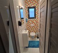 Buntes Badezimmer mit Fliesen und blauem Teppich in einem Einfamilienhaus.