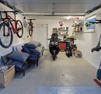 Die Garage des Einfamilienhauses mit Fahrrädern, einem Motorrad und Regalen mit Werkzeugen und Zubehör.