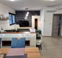 Wohnzimmer mit Fernseher, Holzboden, Sofa und dekorative Wand.