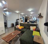 Wohnzimmer in einem Einfamilienhaus mit Sofa, Holztisch und Deckenleuchten.