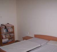 Schlafzimmer mit Bett und Bücherregal, ideal für eine Zweizimmerwohnung.