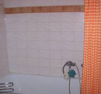 Badezimmer mit Badewanne, orangem Vorhang und Fliesen in einer 2-Zimmer-Wohnung.