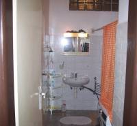 Badezimmer in einer 2-Zimmer-Wohnung mit weißem Waschbecken, Dusche und orangefarbenem Vorhang.